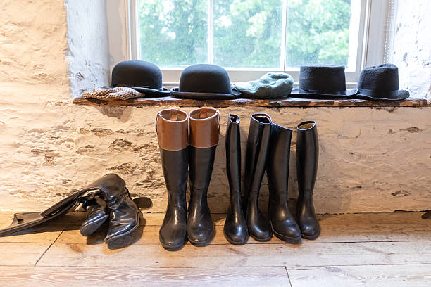 istock Row of black riding boots and hats on a rustic windowsill in a cozy studio 2251693838