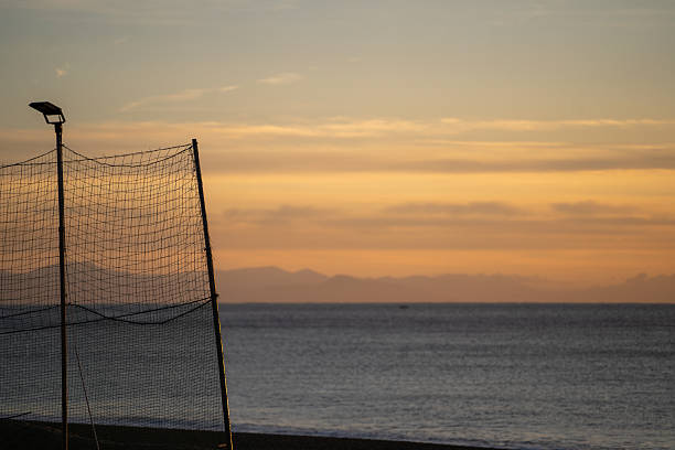 Peaceful Beach View, Serene Seashore Scene With Net And Soft Sky Hues In Background, Quiet Seaside Setting Showcasing Volleyball Net Against Soothing Pastel Sky Backdrop