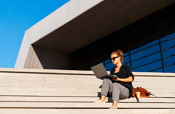 istock Modern female entrepreneur working on laptop outdoors in urban setting 2251695208