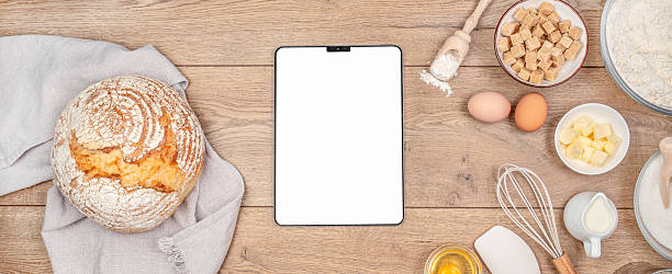 istock Digital tablet on kitchen table worktop on background with bread and utensils. Food recipes, online delivery, homemade food, cooking process 2251695268