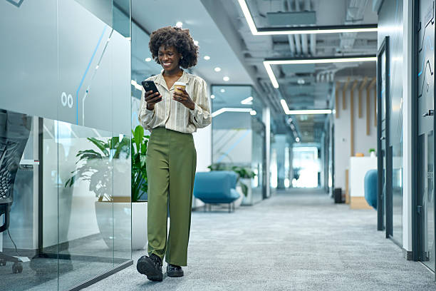 istock Business woman walking through office using phone 2251697028