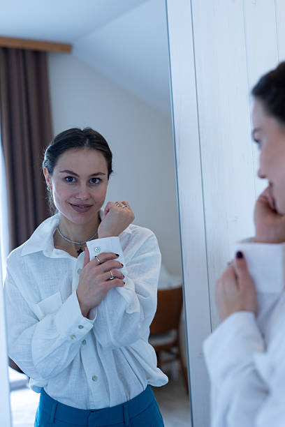 istock Woman adjusting cuff in mirror getting ready for day. Stock image 2251699140