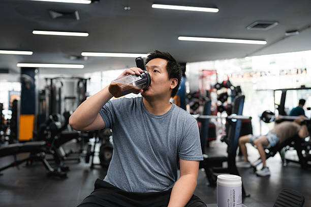 istock Plus-Size Man Drinking Pre-Workout Whey Protein Shake, Sitting Confidently on a Bench Before His Exercise 2251699873