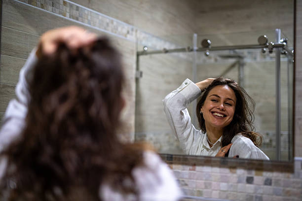 istock Young woman smiling while looking at mirror reflection. Stock image 2251700120
