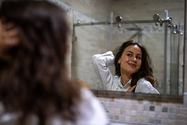 istock Young woman smiling at reflection in bathroom mirror. Stock image 2251700146