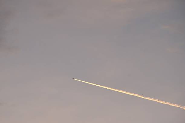 vapor trails from jet plane on sunset sky in evening
