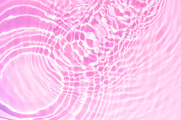 istock Pink water bubbles on the surface ripples. Defocus blurred transparent pink colored clear calm water surface texture with splash and bubbles. Water waves with shining pattern texture background 2251700965