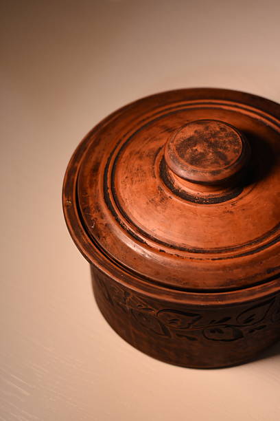 Vertical angled top view of a clay pot with a closed lid, placed to the side of the frame. Minimal rustic concept.