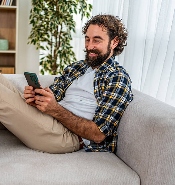 istock Happy man relaxing on couch using smartphone 2251715183