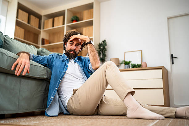 istock Man feeling sad and stressed sitting on living room floor 2251715773