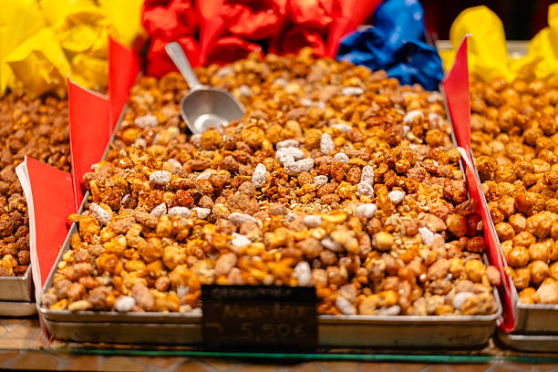 A close-up view of freshly caramelized mixed nuts displayed in a metal tray at a festive market stall.