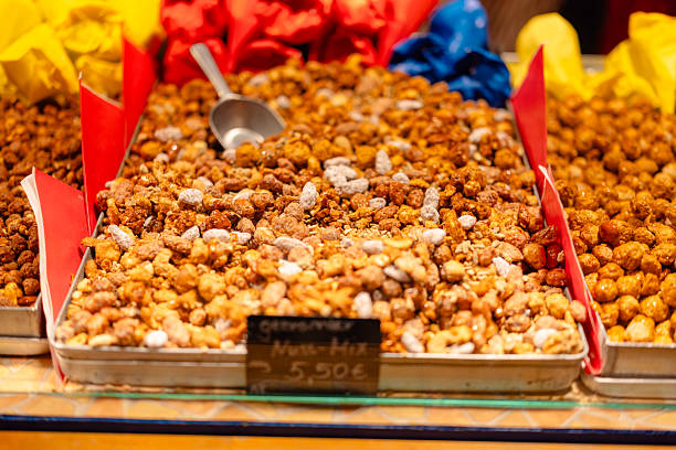 A close-up view of freshly caramelized mixed nuts displayed in a metal tray at a festive market stall.