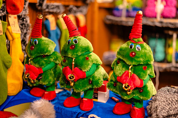 Cute plush Christmas tree toys with red hats and tiny saxophones displayed at a Berlin Christmas market. A colorful and festive holiday merchandise scene.