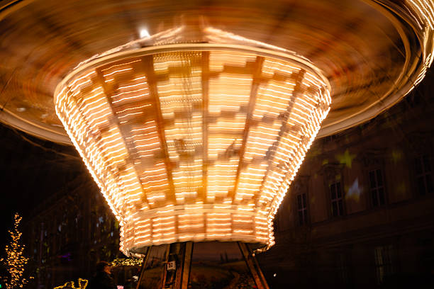 Motion blur photograph of a spinning carousel at a Christmas market, creating warm light trails and festive atmosphere