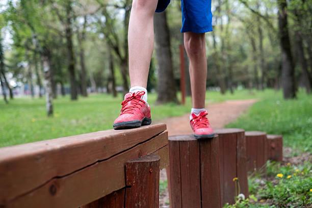 Child balancing on a wooden beam, developing motor skills outdoors