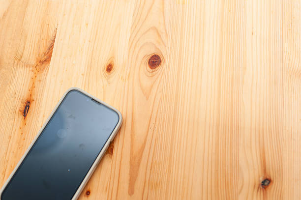 A smartphone rests a natural wood surface highlighting a minimalist design in a cozy indoor environment.