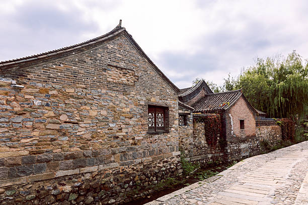 Gubei Water Town stone gate tower with arched passage and wooden pavilion architecture along pathway in China