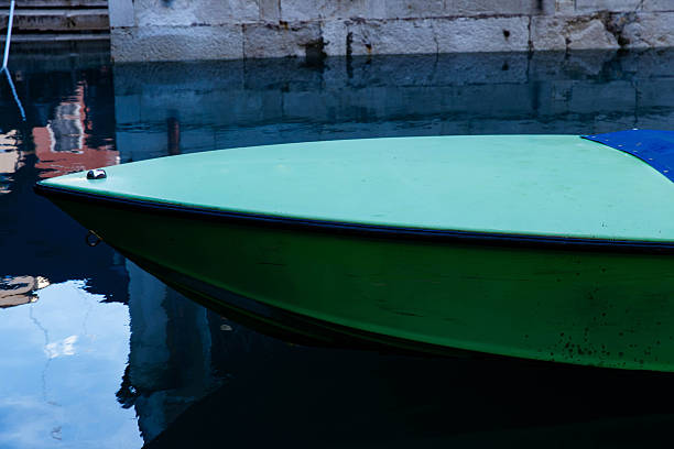 Green speedboat bow reflected on still water