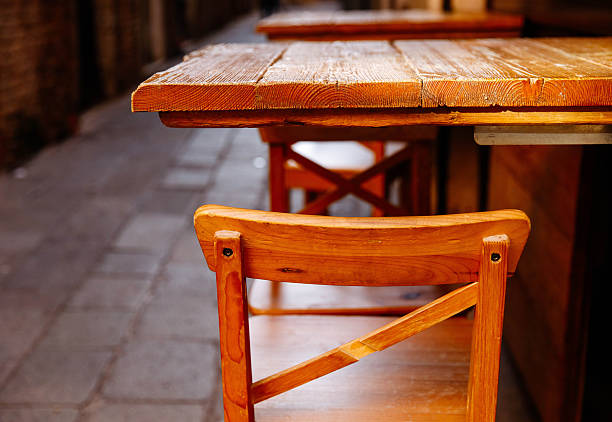 Empty rustic wooden cafe tables and chairs in narrow alley