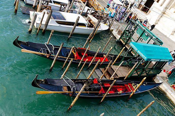 Venice, Italy - December 05, 2025: Gondolas are moored at a lively Venice waterfront, highlighting the beautiful architecture and vibrant ambiance of the city