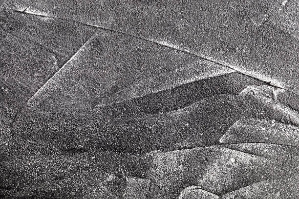A black plastered, uneven wall with white chalk forming various lines, suitable for a background for a picture.