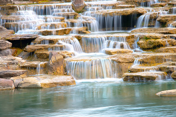 Landscape with small waterfall and lake in canyon. Gray stones in front