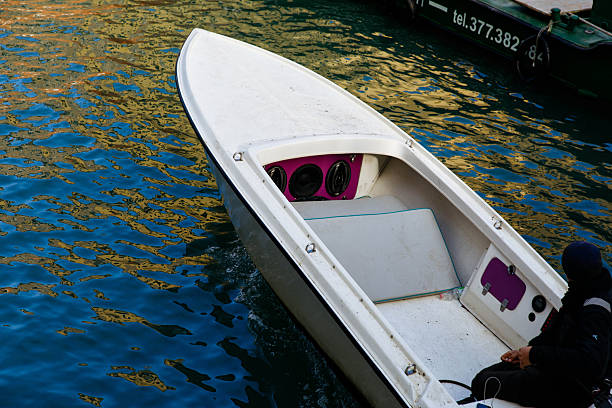 Venice, Italy - December 05, 2025: Small motorboat is moving across calm blue water, reflecting sunlight and creating a tranquil scene in a coastal environment