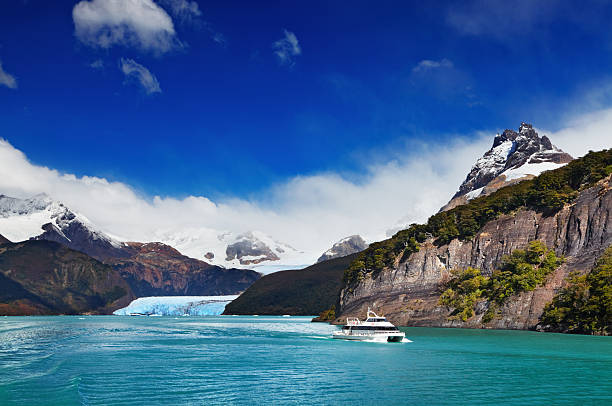 An iceberg floats on the surface of Lake Argentino, with the Patagonian Andes in the background.