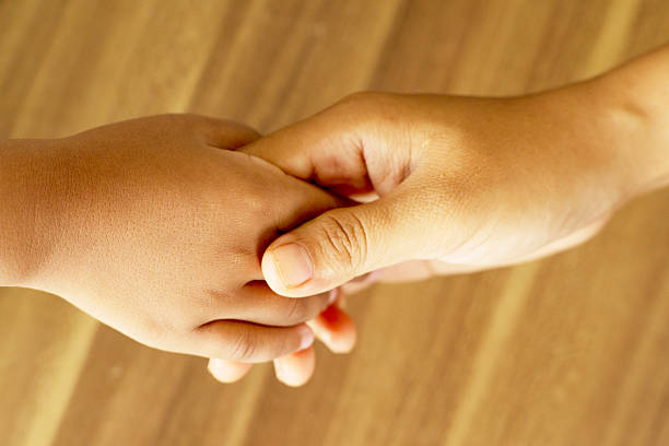 Closeup, couple and holding hands on grass for care with bonding, relax and partnership in backyard of home. People, love and support on lawn in garden of house or park with kindness and relationship