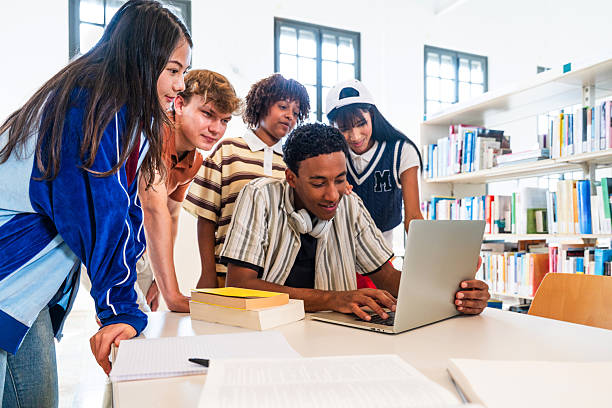 istock Multiethnic group of young students collaborating using laptop in library 2251746845