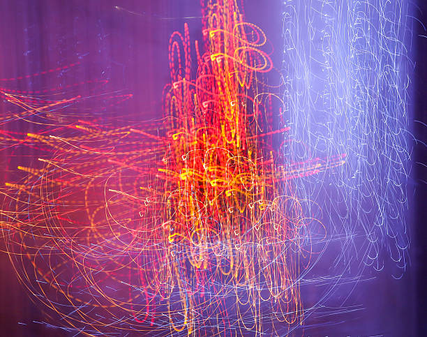 Vertical abstract light painting creates a rich and dynamic background featuring fiery red and golden-yellow light trails. Long exposure captures a multitude of intertwined lines and spots, mimicking an energy burst or chaotic nightlife.