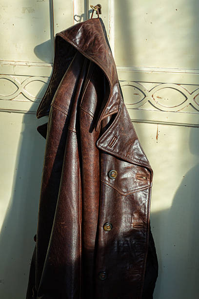 istock Vintage Brown Leather Jacket Hanging on Wall Hook with Natural Sunlight Shadow 2251749475