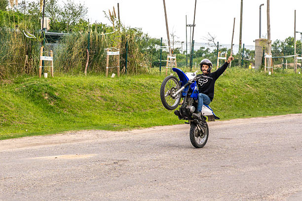 A motorbike parked by the roadside, with a blue sky and white clouds in the background