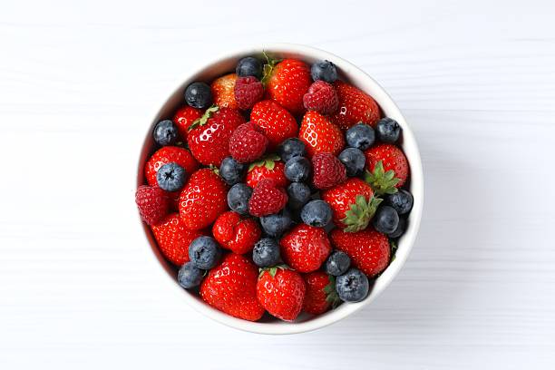 istock Different fresh ripe berries in bowl on light table, top view 2251768434