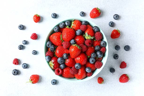 istock Different fresh ripe berries in bowl on light table, top view 2251768466