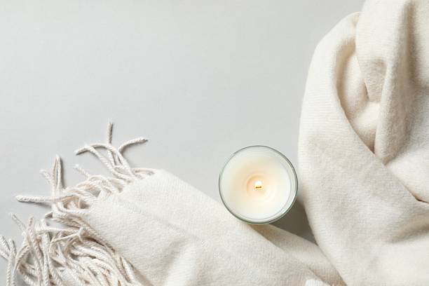 istock Beige scarf with birning candle on a gray background 2251769494