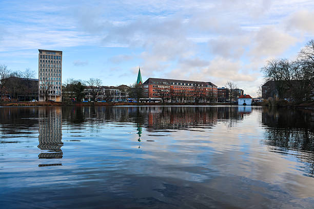 Kiel, Germany - 13. December 2025: Urban buildings reflecting in calm water under a cloudy sky in Kiel, Germany