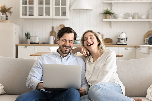 istock Joyful carefree couple sit on couch browse websites on notebook 2251770864