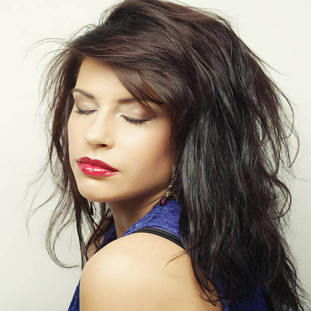 portrait of beautiful young woman playing with her hair in gray color background