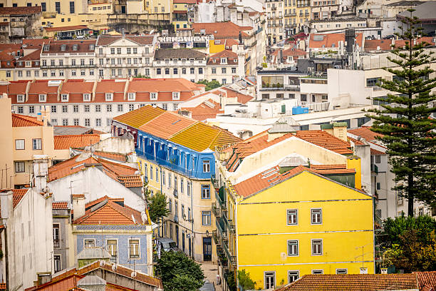 Lisbon Portugal December 05 2025. Blue and yellow residential buildings are seen among hillside homes in central Lisbon under cloudy light.