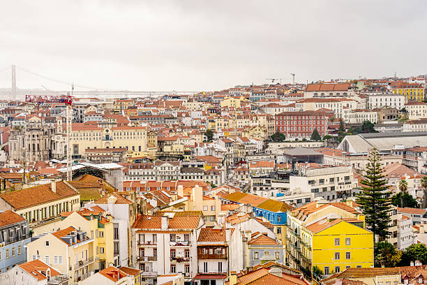 Lisbon Portugal December 05 2025. A hillside of residential buildings and historic structures is visible under cloudy sky conditions.