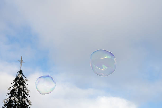 A large soap bubble drifts above historic Lisbon buildings on a clear winter day creating a light colorful reflection in the sky