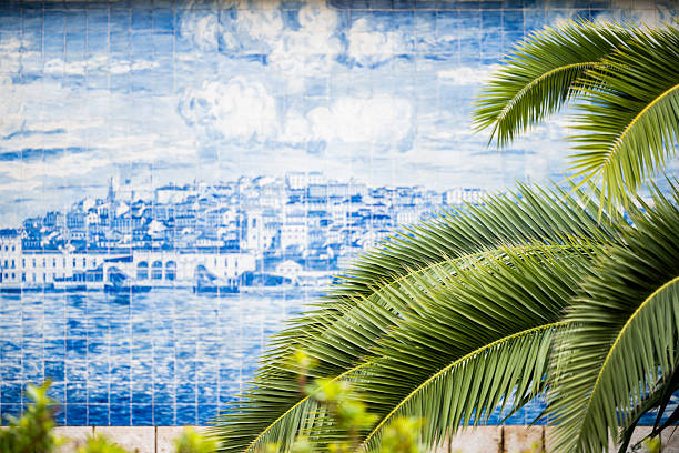 Lisbon Portugal December 05 2025. Palm leaves partially obscure a large painted tile mural depicting the Lisbon waterfront.