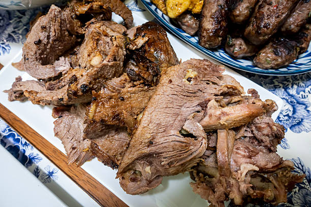 Tender meat is displayed in a tray at a bustling food stall.