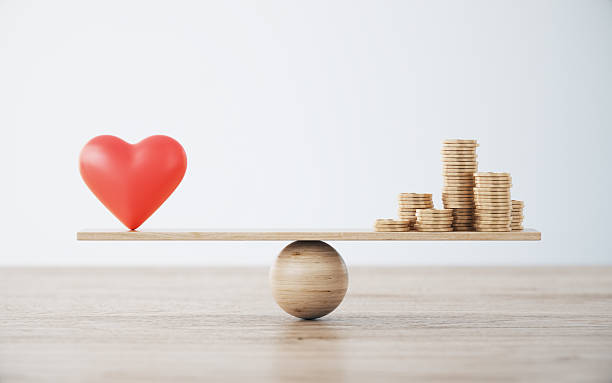 istock Heart Shape and Gold Coin Stack On Wooden Seesaw. 2251790432