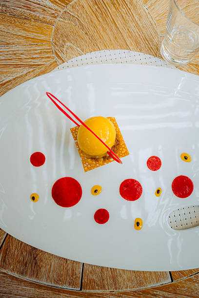 istock Mango sorbet dessert with red fruit coulis on a white plate 2251792423