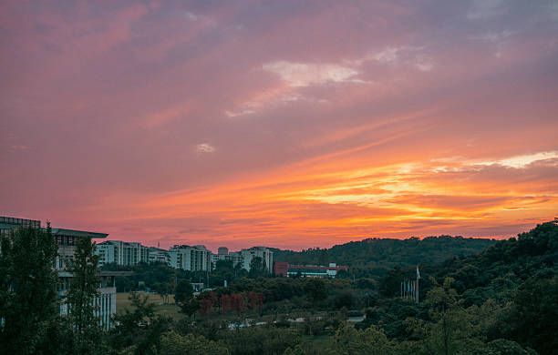 A picturesque sunset scene featuring buildings under a sky filled with vibrant orange and pink clouds.