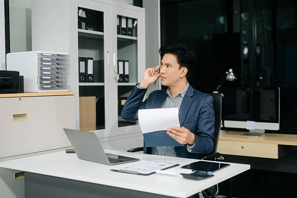 istock Handsome man typing on tablet and laptop while sitting at the working wooden table modern office 2251801159