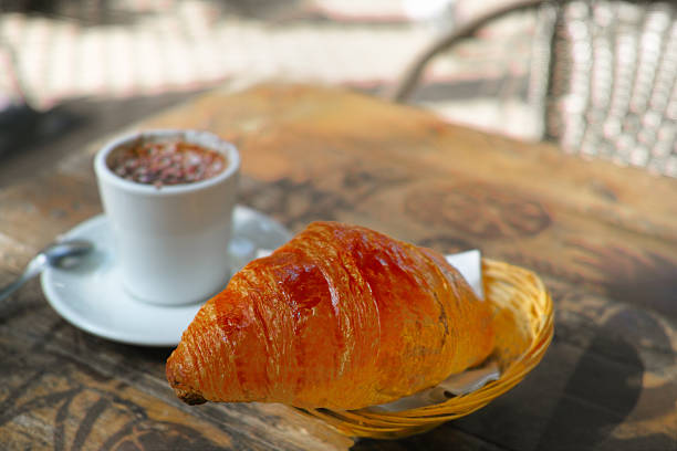 freshly baked croissant next to the cup of coffee or chocolate, a morning light shot