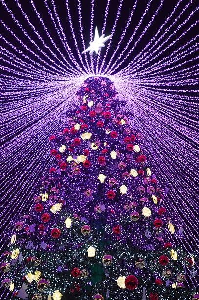 This vibrant scene unfolds with a digital representation of Christmas festivities, as a pixelated cityscape comes to life beneath a radiant particle Christmas tree. The gathering crowd, composed of diverse digital avatars, adds a lively touch to the bustling urban setting, encapsulating the spirit of a tech-infused holiday celebration.4K 3D rendering.